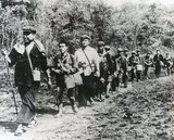 In a staged photograph, a troop of Khmer Rouge guerrillas file through the jungle of western Cambodia. Pol Pot strides out in the lead, followed by his personal bodyguard and then Brother No 2, Nuon Chea. Ieng Sary (in black) is 11th from left. The message to the Vietnamese and the outside world: "We're still here and a viable force".