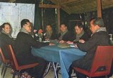 Wearing black peasant garb, chequed krama and with their Chinese military caps resting on the table, from the left closest to the map are Ieng Sary and then Hou Yuon. On the other side of the table, from the left are Pol Pot, Hou Nim and Khieu Samphan. At the end of the table sits Sihanouk.